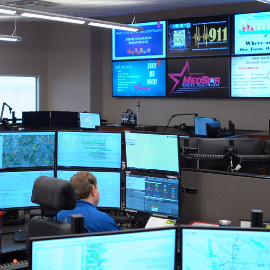 Telecommunicator working in a 911 Public Safety Answering Point (PSAP) with multiple screens